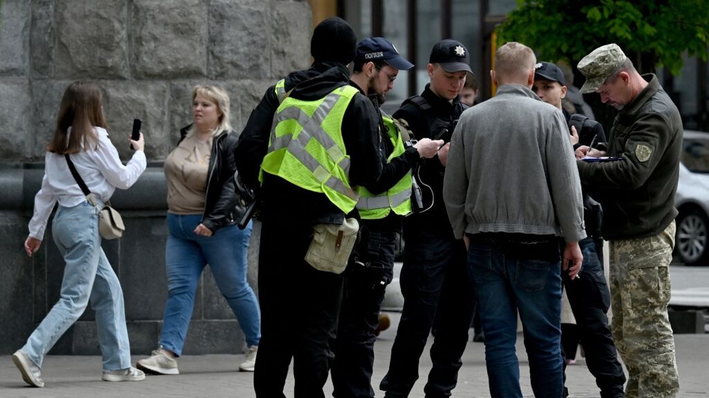 Mobilisatie-politie controleert documenten van een man in Kyiv. Foto: Sergei Supinsky / AFP