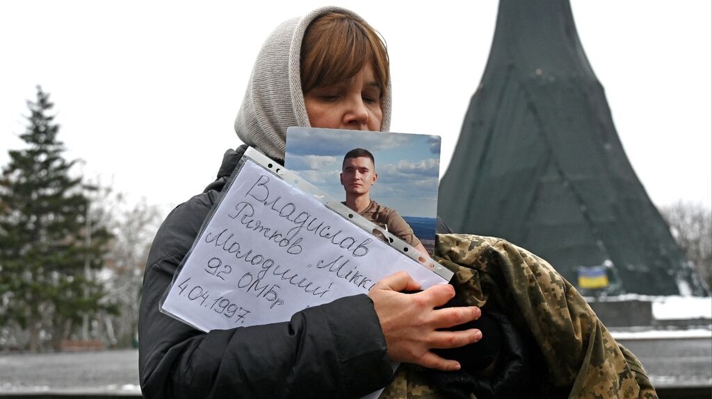 A woman holds the portrait and the military uniform of her fallen son during the commemoration event of fallen Ukrainian soldiers in the center of Kharkiv, on December 6, 2024. Photo: Sergey Bobok / ANP / AFP